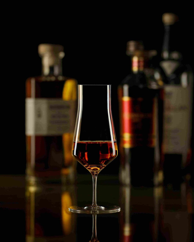 Bicchiere Zalto Denk'Art Cask con whisky e bottiglie sullo sfondo